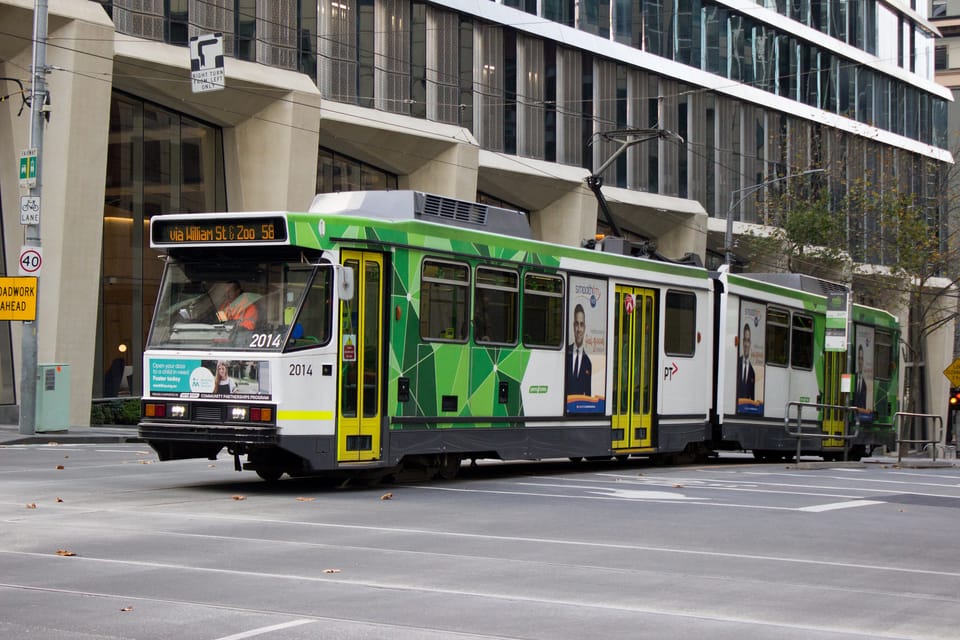 A photo of a B class tram passing underneath a hook turn sign on William Street at Collins Street in Melbourne, Australia