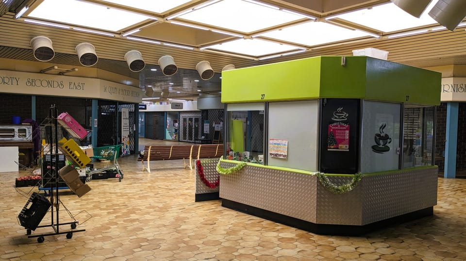 Photo of the interior of Mooroolbark Terrace Shopping Centre, empty with a small abandoned cafe building in the centre.