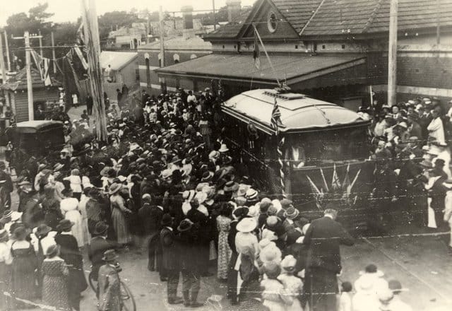 Black and white photo of an electric tram surrounded by crowds of people outside Sandringham Railway Station in 1919.