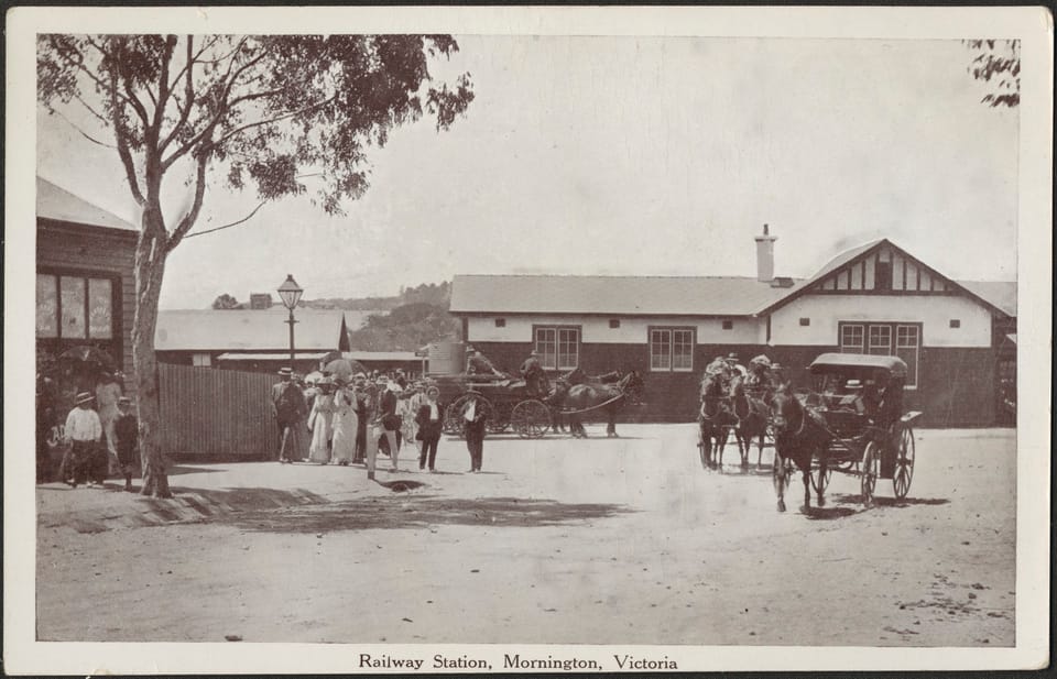 Black and white photo of Mornington Railway Station with people and horses and carts in front from the early 20th century